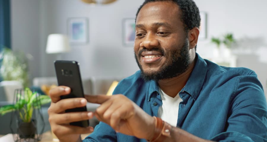 Man at home navigating an app on his cell phone